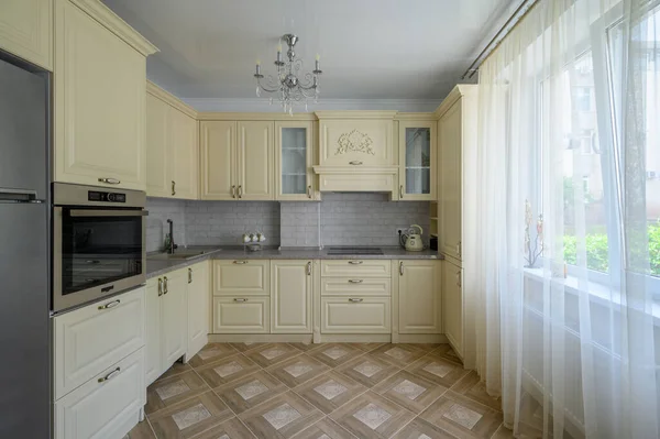 Real showcase interior of modern trendy cream colored kitchen