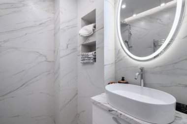 Beyaz banyo içi mermer kaplamalı ve yuvarlak aynalı.