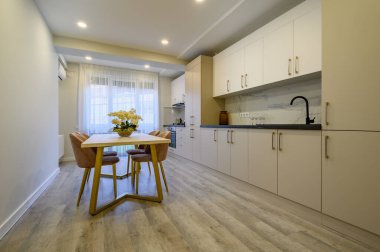 Geniş bir bej ve krema mutfağı ve yemek masası.