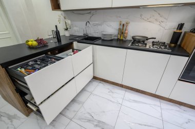 Büyük siyah ve beyaz modern mutfak iç mimarisi, yüksek açılı köşe manzarası, bazı çekmeceler çıkarılmış.