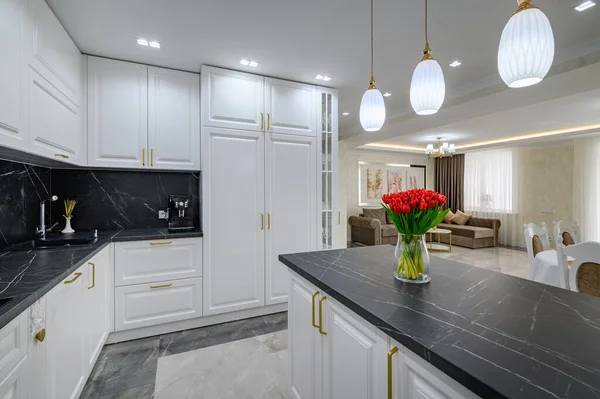 大的黑白昂贵的现代厨房在工作室的内部设计精美 黑色大理石台面在厨房岛上的花束红花 — 图库照片