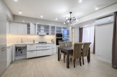 Stüdyo dairenin yenilenmesinden sonra beyaz, yeni, iyi tasarlanmış, pencereleri perdeli beyaz mutfak.