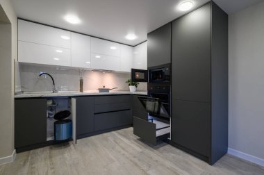 Showcase interior of modern simple dark grey and white kitchen, drawers retracted, doors open