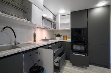 Closeup details of showcase interior of modern simple trendy dark grey and white kitchen, drawers retracted