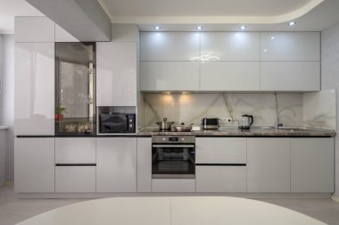 Interior of well designed modern trendy white kitchen, front view