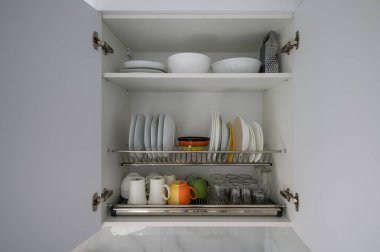 Tabaklar, kaseler, bardaklar ve bir sürü fotokopi odası olan geniş beyaz mutfak dolabını aç.