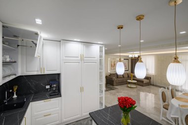 Closeup to black granite worktop of white domestic kitchen with marble floor and kitchen island