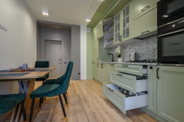 Modern trend açık yeşil lüks mutfak, yemek masası ve koyu yeşil sandalyeler, bazı çekmeceler geri çekilir