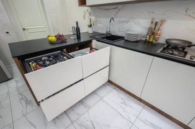 Büyük siyah ve beyaz modern mutfak iç mimarisi, yüksek açılı köşe manzarası, bazı çekmeceler çıkarılmış.