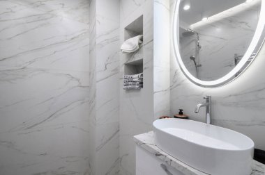 Beyaz banyo içi mermer kaplamalı ve yuvarlak aynalı.