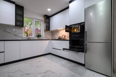 Beyaz, modern bir tasarımı ve lüks mermer zemini olan parlak ve havadar bir mutfak. Açık fırın kapısı biraz sıcaklık ve rahatlık katar..