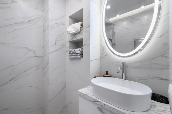白色浴室内部墙壁上有大理石瓷砖和一面圆形镜子 — 图库照片