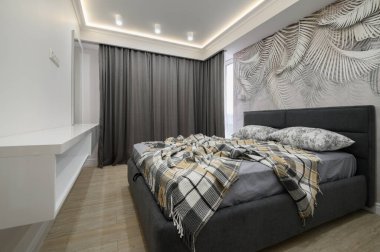 Gri yatak odasının şık, rahat çift kişilik yatağı var.