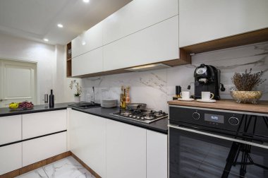 Beyaz ve siyah lüks modern mutfak ayrıntıları, fırın, kahve makinesi ve diğer aletlerle atölyeye yakın çekim