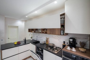 Büyük siyah beyaz modern mutfak, köşe manzarası, bazı mobilya kapıları açık.