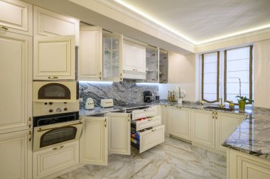 Donanım, çekmece ve dolap kapıları açık olan krem renkli bir mutfağa yakın çekim.