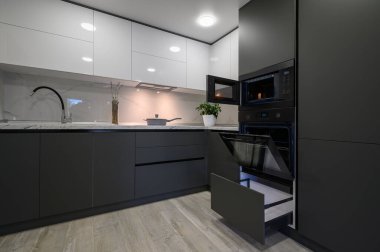 Modern basit, modaya uygun, koyu gri ve beyaz mutfağın içini gösteren çekmeceler geri çekildi