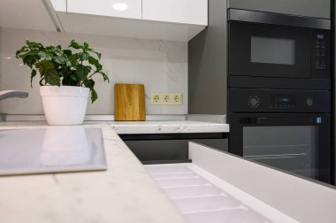 Modern koyu gri ve beyaz mutfağın mermer atölyesine yakın, pişirme tavası gaz ocağında, dolap çekmeceleri geri çekildi