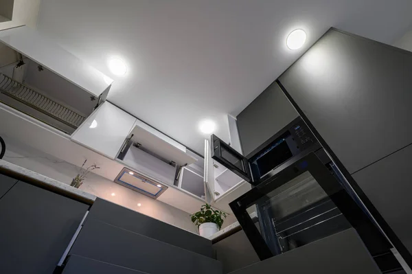 Closeup details of showcase interior of modern simple dark grey and white kitchen, drawers retracted, low angle view