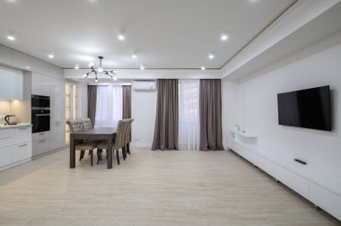 Stüdyo daire, televizyon, bir sürü fotokopi odası, perdeli büyük pencereler ve sandalyeli yemek masası.