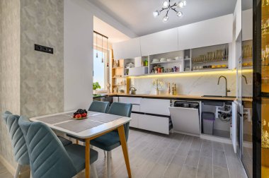 A sleek modern white kitchen with drawers pulled out and doors open