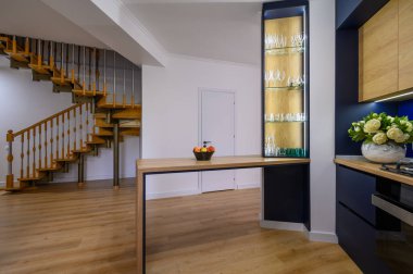 From kitchen to entrance hall view in studio apartment with stairs at background