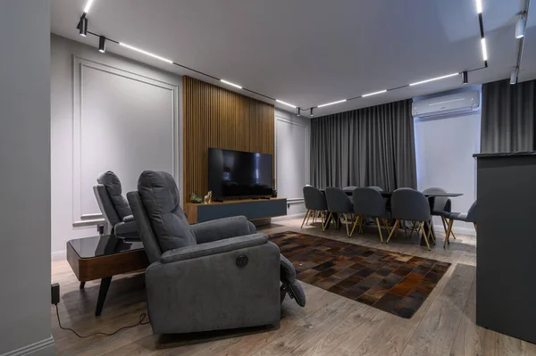 Luxury living room with massage chairs and grey kitchen in studio apartment interior