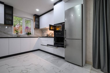 A contemporary kitchen with white cabinets, a marble floor, and an open oven door. Perfect for cooking, entertaining, and enjoying life.