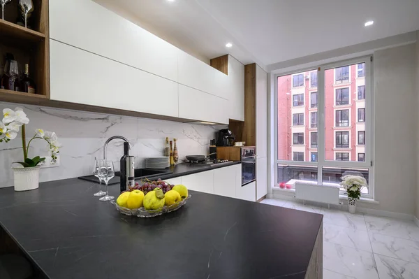 Stock image Black and white modern luxury kitchen interior, closeup to worktop with fruits and wine in the foreground