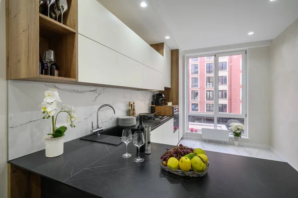 stock image Black and white modern luxury kitchen interior, worktop with fruits and wine in the foreground