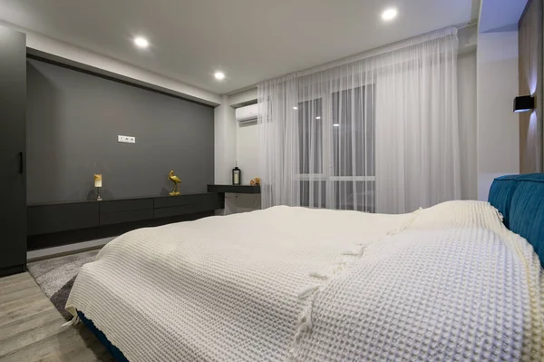 Modern master bedroom with trendy gray and white interior, large king-size double bed