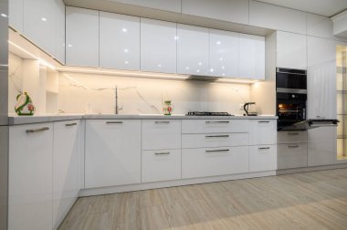 Interior of a modern white kitchen in luxury studio apartment, close-up view of kitchen furniture