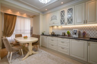 Geniş bir yemek masası ve son model aletleri olan güzel bej bir mutfak.