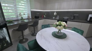 Modern trendy white and gray kitchen with small round dining table, tilt shot