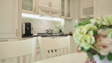 Büyük lüks bej renkli, modaya uygun klasik mutfak, üzerinde çiçekler olan beyaz yemek masası.