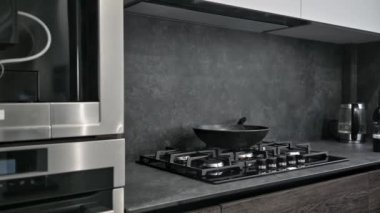 Modern koyu kahverengi, gri ve siyah mutfağın gaz ocağı ve çalışma odası.
