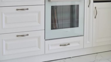 Modern klasik lüks beyaz mutfak hareketinin yakın çekim kamera hareketi fırın, mikrodalga fırın, gaz sobası ve birden fazla çekmece ve kutu ile
