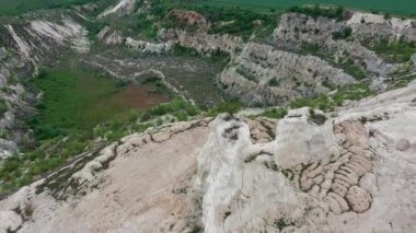 Aerial view to limestone Quarry near Fetesti village in Moldova, Eastern Europe, orbiting around lonely tree left at the top of rock, group of unrecognizable people on the ground