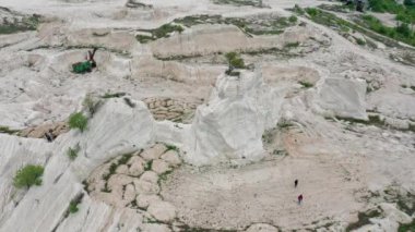 Aerial view to limestone Quarry near Fetesti village in Moldova, Eastern Europe, orbiting around lonely tree left at the top of rock, group of unrecognizable people on the ground