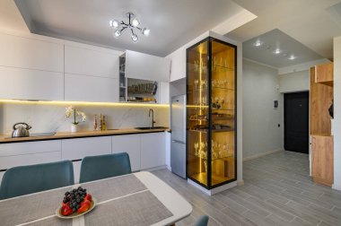 A sleek white studio apartment with a fully functional kitchen and a stylish glass sideboard