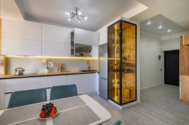 A fashionable white studio with a modern kitchen and a sleek glass sideboard