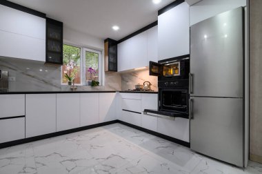 A luxurious, modern kitchen with a white color palette, a marble floor, and an open oven door. Perfect for cooking, dining, and enjoying life.