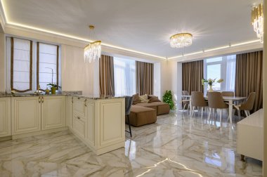 Klasik bir mutfak ve oturma odası. Geniş ve parlak krem rengi bir tasarımı var. Bir stüdyo dairede, ada ve yemek alanı ile birlikte.