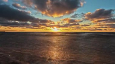 Baltık Denizi 'nin Sunset, Pavilosta, Letonya' daki Timelapse Manzarası. Sahildeki Deniz Burnu 'nun Üzerinde Güzel Altın Gün Batımı. Parlayan Güneş Işığı Yansıması. Courland 'daki Saka Nehri' nin ağzındaki Baltık Denizi