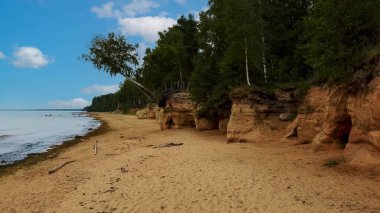 Veczemju Kayalıkları Kızıl Kayalar, Letonya. Baltık Denizi kıyısındaki Kızıl Kum Taşı Uçurumu 'nda Dalgalar, Kayalar ve Bulutlu Yağmurlu Yaz Günü. Hava Görünümü