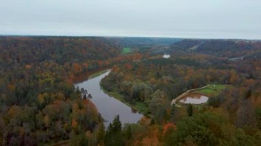 Letonya 'nın Sigulda şehrinde Gauja Nehri yakınlarında sonbahar. Renkli Ormanlar ve Vadi İHA 'sı Gauja Ulusal Parkı' nı vurdu. Şeytan Uçurumu Köprüsü Gauja Nehri üzerinde Kayak Resort Kakitis 'ten görünüyor