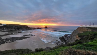 Günbatımı Zambujeira Do Mar Plajı, Alentejo, Portekiz. Portekiz Yürüyüşü Rota Vicentina Balıkçı Yolu boyunca Alentejo Kıyısı boyunca Vahşi ve Engebeli Sahillere Dar Sahil Yolları.