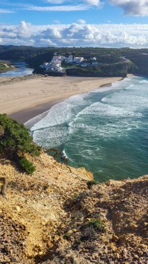Praia De Ohexe Mar Sahili Altın Kum, Atlantik Okyanusu, Nehir Bükme ve Aldatma Köyü 'nün Beyaz Evleri ile. Rota Vicentina Sahili, Odemira, Portekiz. Rota Vicentina 'nın Balıkçı Patikası' nda yürüyüş.