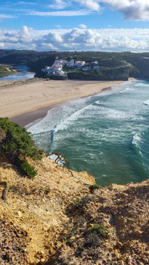 Praia De Ohexe Mar Sahili Altın Kum, Atlantik Okyanusu, Nehir Bükme ve Aldatma Köyü 'nün Beyaz Evleri ile. Rota Vicentina Sahili, Odemira, Portekiz. Rota Vicentina 'nın Balıkçı Patikası' nda yürüyüş.