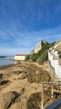 Ortaçağ Kalesi Forte De Sao Clemente 'nin güneşli bir günde Mira Nehri üzerinde açık mavi gökyüzü olan küçük bir tekne manzarası. Vila Nova De Milfontes, Portekiz, Rota Vicentina Sahili. Balıkçı Patikası